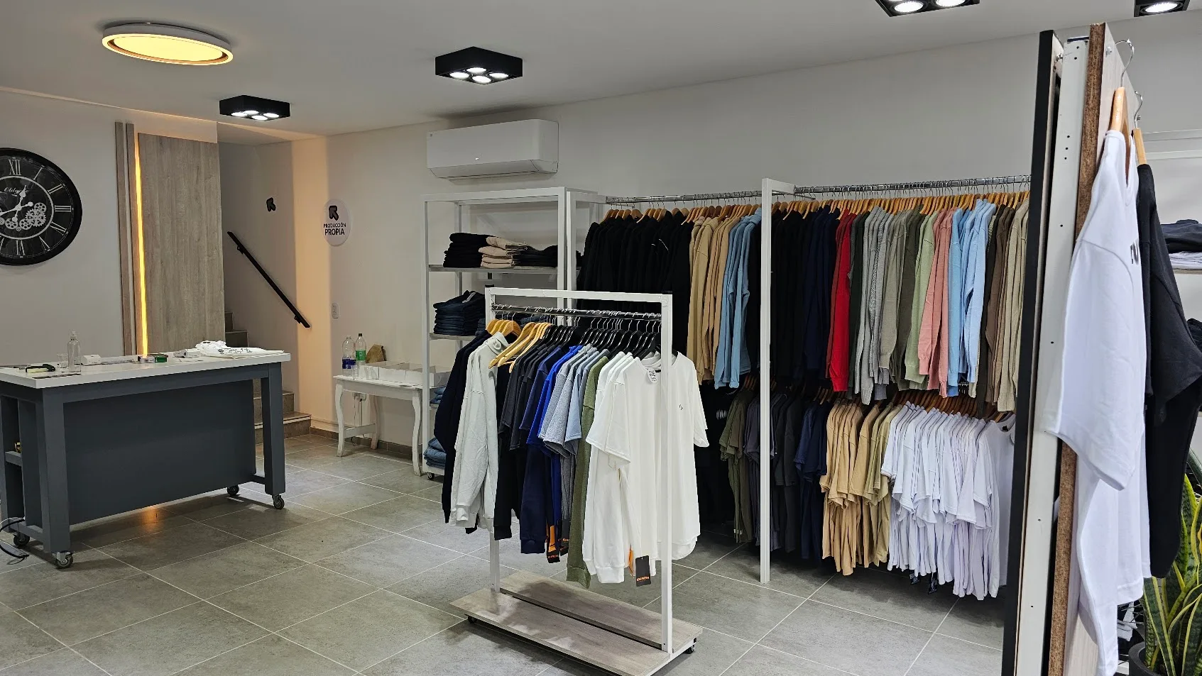 Interior del local de indumentaria: mobiliario blanco, iluminación y exposición de prendas