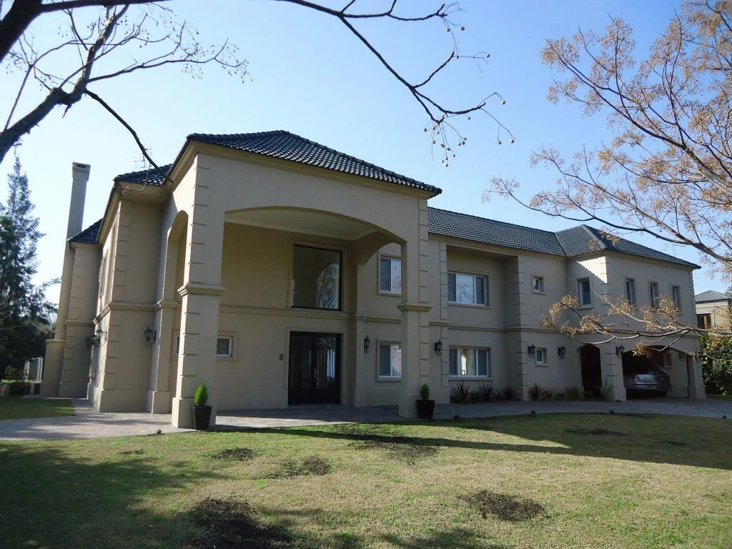 Fachada principal de Casa Los Pingüinos I, con acceso de doble altura y cubierta de tejas.