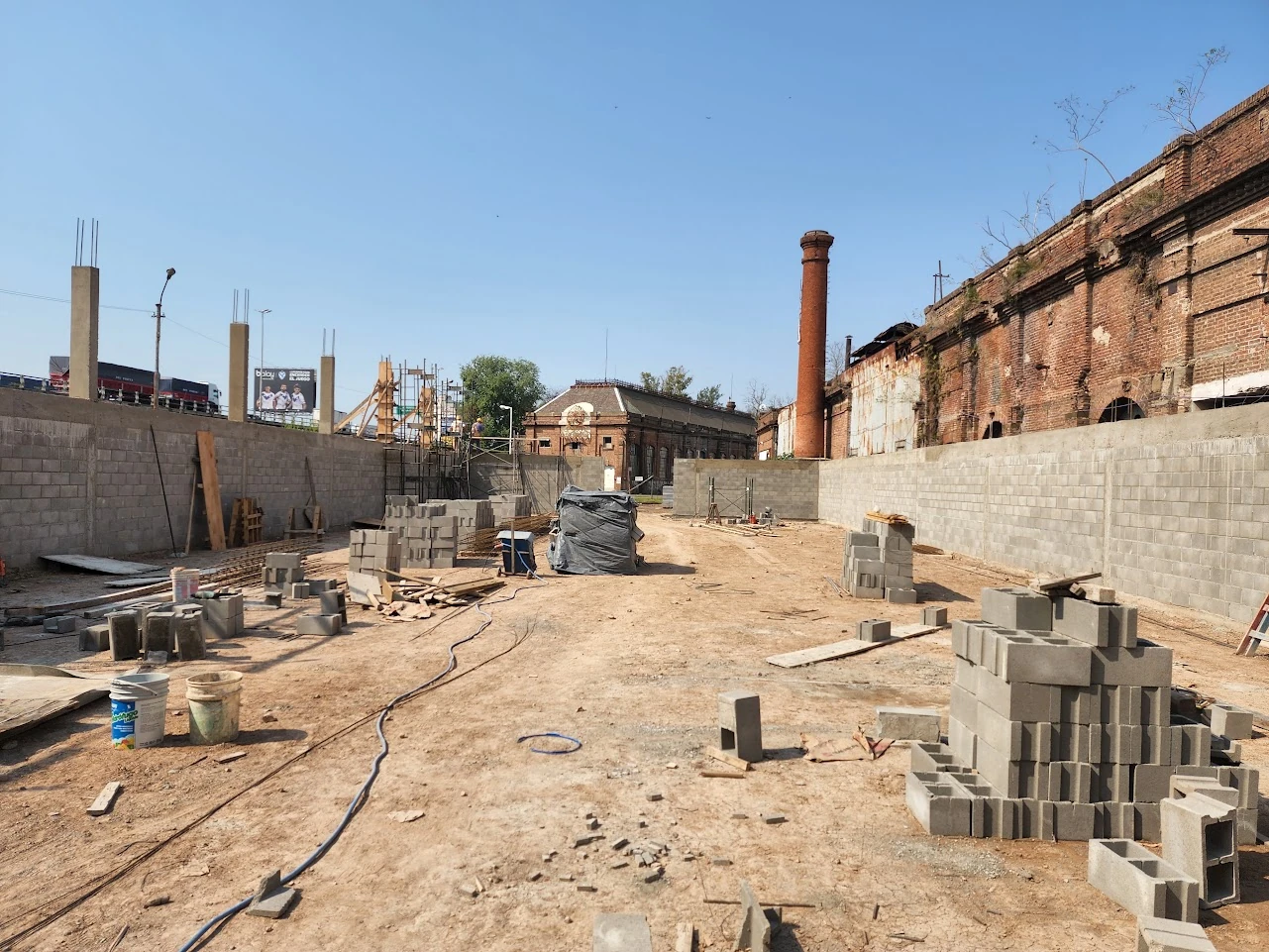 Muros del galpón en ejecución junto a edificaciones de ladrillo existentes.