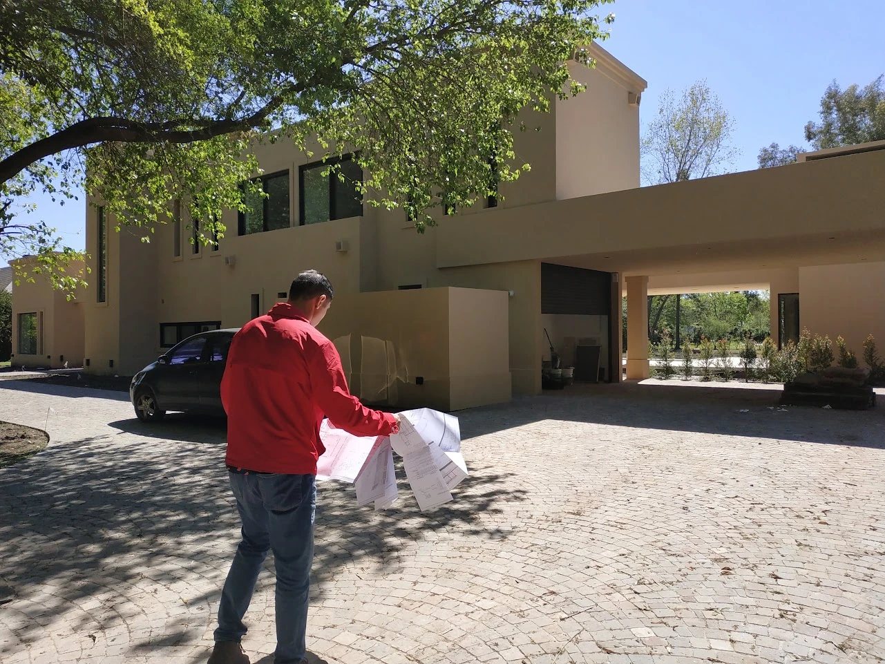 Revisión de planos frente a la vivienda durante una visita de obra.